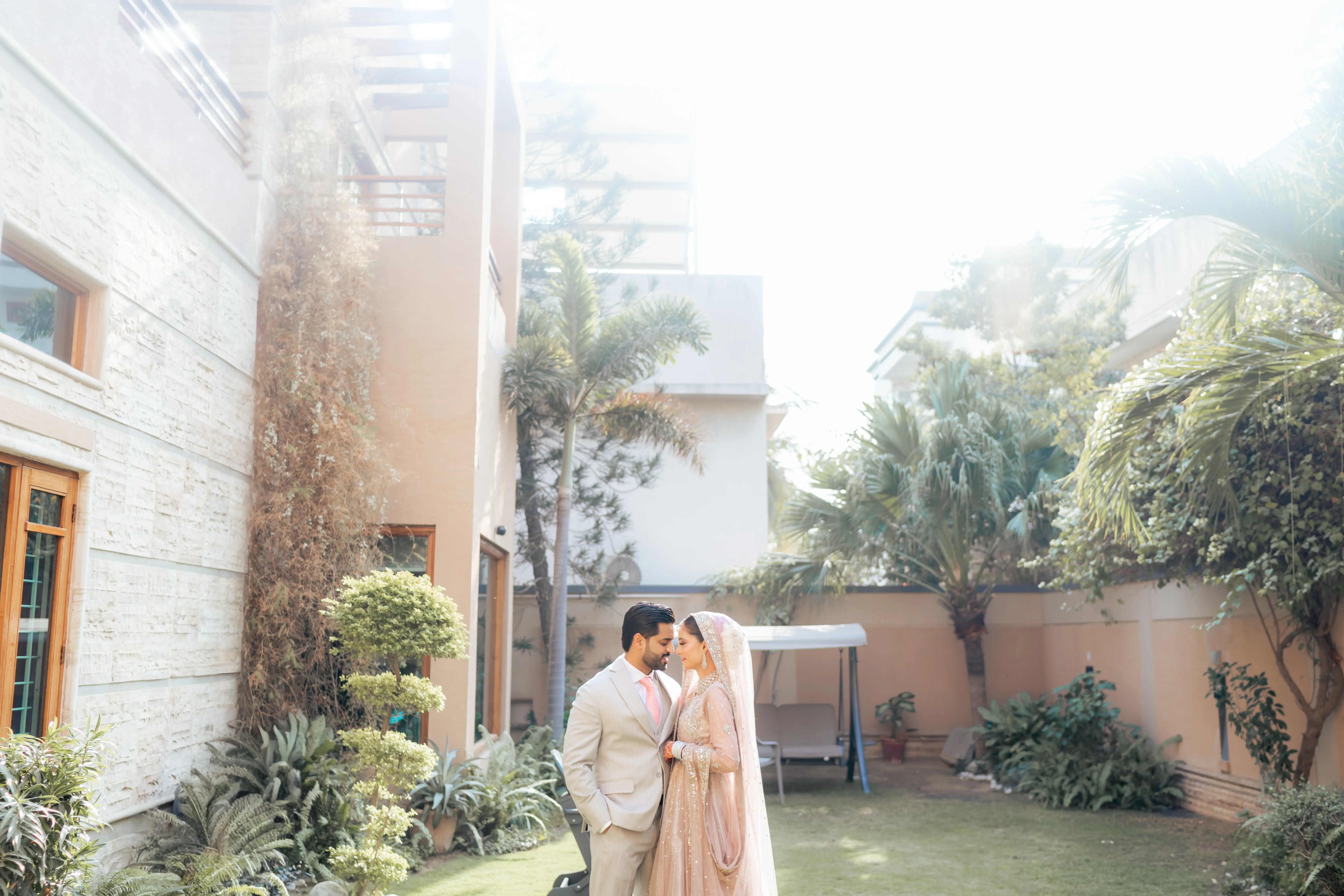 Bride and groom walking through a sunlit gallery hall